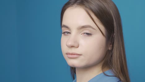 Ukrainian-young-woman-looking-dull-at-camera.-Blue-background.